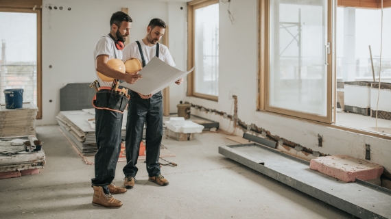 Handerwerker analysieren Plan auf der Baustelle.